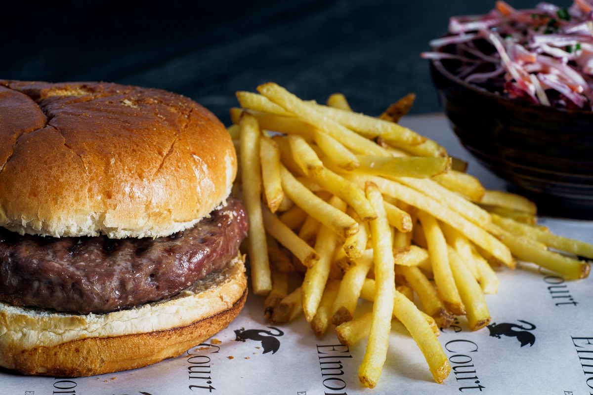 Grilovaný hovädzí burger s hranolčekmi na drevenej doske